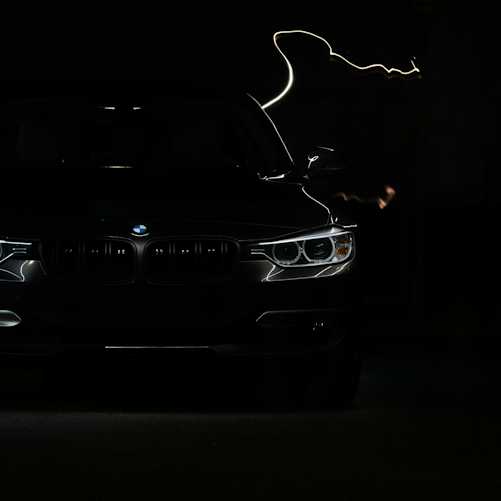 Illustrative dark luxury car silhouette with headlights on, representing the transition to electric luxury vehicles.