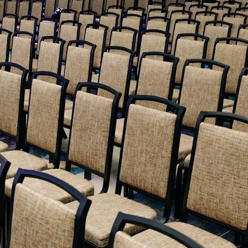 Rows of empty chairs in a large hall; a general conference illustration, not the FII conference venue or evidence of cancelled attendance.