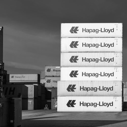 Stacks of Hapag-Lloyd shipping containers at an industrial European port, illustrating EU–China goods trade; not a photograph of the Dublin ministers' meeting.