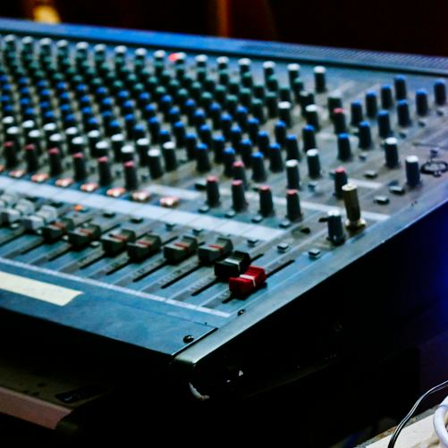 Illustrative close-up of an audio mixing console, representing public-service broadcasting equipment; not the studios of Czech Television or Czech Radio.